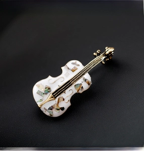 Macro detail of cello brooch with colorful shell inlay and gold metal strings on leather