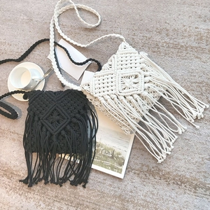Détail de sacs bohèmes tissés main avec pompons et motifs géométriques sur un tapis