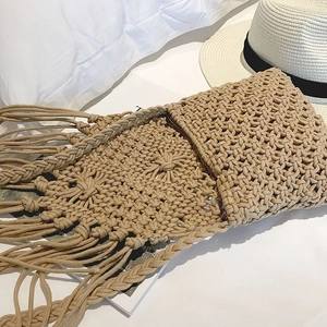 Vue détaillée du sac en coton tressé fait main avec franges sur literie blanche