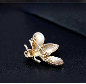 Macro view of the gold bee brooch back showing the secure pin clasp and metal texture