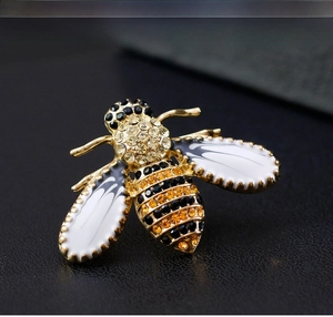 Macro shot of bee brooch with yellow rhinestones and white enamel on a dark background