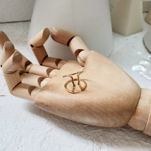 Artistic gold abstract face ring displayed on a wooden mannequin hand with minimalist design