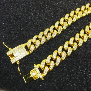 Close-up of 12mm 18K gold-plated Cuban link bracelet with iced-out rhinestones and box clasp