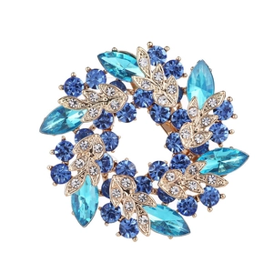 Close-up of golden vintage flower brooch featuring navy and light blue crystal petals