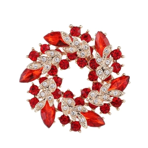 Detailed view of a golden wreath brooch with vibrant red marquise and round crystals