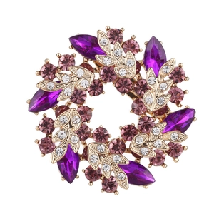 Detail of golden floral brooch featuring purple rhinestones and marquise crystal leaves