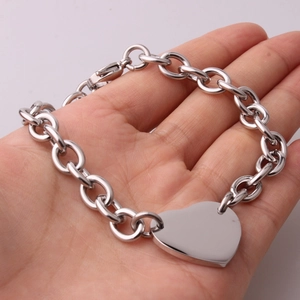 Close-up of heart charm bracelet in stainless steel held in hand with silver finish