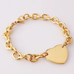 Detail of chunky gold chain bracelet with polished heart pendant and lobster clasp