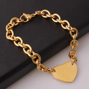 Detailed close-up of golden heart pendant on stainless steel chain link bracelet