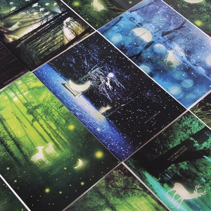 Detailed flat lay of forest and deer greeting cards in blue and green tones
