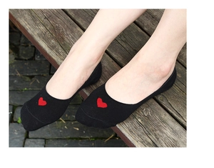 Gros plan de socquettes noires en coton pour femmes avec broderie coeur rouge sur le pied