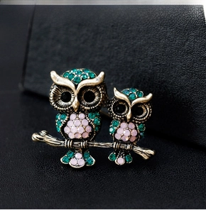 Macro detail of retro owl brooch featuring green rhinestones and vintage bronze finish