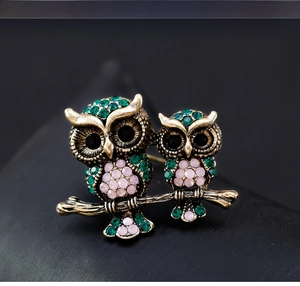 Detailed view of vintage gold owl brooch with sparkling green and pink rhinestones