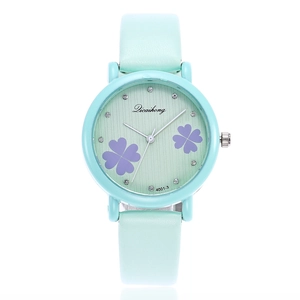 Detail of mint green watch featuring a textured dial with purple four-leaf clovers and crystals