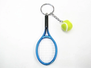 Macro detail of a blue mini tennis racket and yellow ball keychain with silver ring