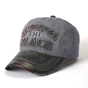 Close-up of vintage washed cotton baseball cap with embroidered text and leather trim