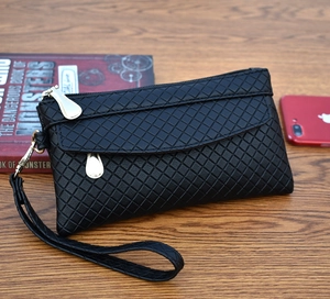 Close-up of black quilted weave clutch purse with gold zipper and wrist strap detail