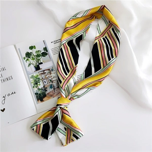 Detail of a narrow silk scarf with yellow, black, and red stripes knotted on a magazine