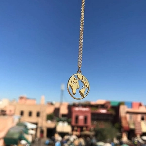 Detail of a 925 sterling silver gold world map pendant against a blue sky background