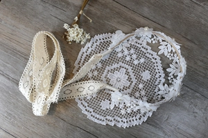 Detalle de diadema de encaje blanco con perlas y cintas largas sobre fondo de madera