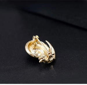 Macro view of the golden metal snail brooch showing the pin back structure detail