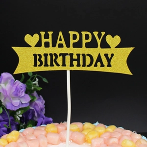 Macro detail of golden glitter Happy Birthday cake topper with two heart shapes