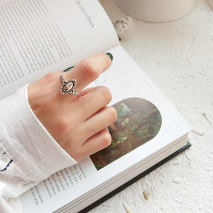 Macro shot of vintage silver ring featuring olive green gemstone on open book
