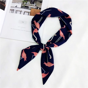 Dettaglio di sciarpa in seta blu navy con stampa fenicottero annodata su rivista