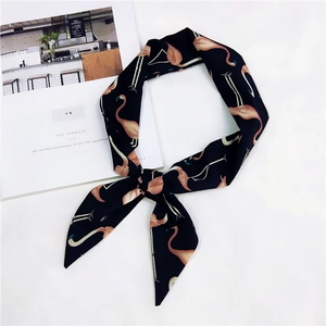 Dettaglio di un foulard in seta nero con fenicotteri rosa annodato su una rivista aperta