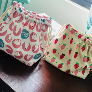 Détail des sacs à cordon en coton avec motifs d'ours polaire et de fraises sur bois