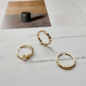 Detailed view of three-piece gold love ring set with leaf and geometric patterns