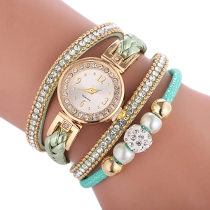 Détail de la montre bracelet à enroulement vert menthe avec strass et perles sur le poignet