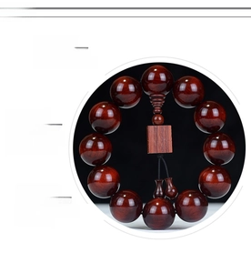 Close-up of polished Red Sandalwood prayer beads with a wooden pendant and intricate grain