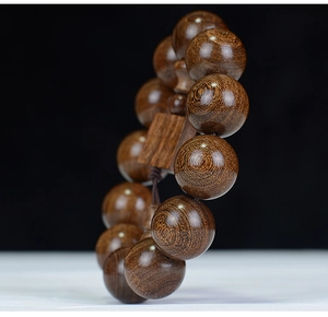 Macro detail of natural grain on dark brown sandalwood prayer beads with polished texture
