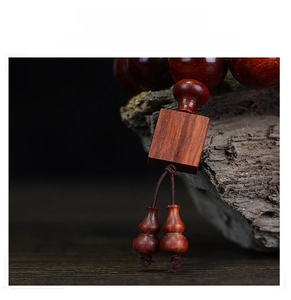 Macro detail of sandalwood beads with square spacer and double gourd pendant on dark wood
