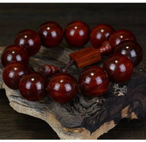Macro shot of polished red sandalwood beads with natural grain and rectangular charm