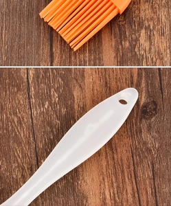 Macro detail of heat-resistant orange silicone bristles and white handle with hanging hole