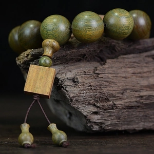 Echtes grünes Sandelholz-Armband mit buddhistischen Perlen auf Holzuntergrund