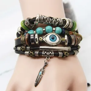 Detail of bohemian leather bracelet with evil eye charm, feathers, and green beads