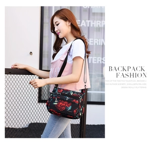 Detail of multi-layer zipper compartments on floral printed nylon crossbody bag