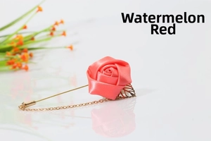 Detailed close-up of watermelon red silk rose brooch with golden leaf and chain detail