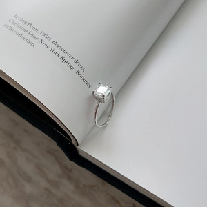 Macro detail of square cut solitaire ring in S925 sterling silver nestled in book pages