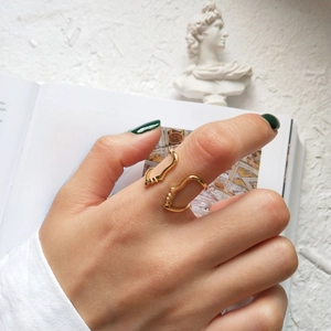 Artistic close-up of an abstract wavy gold ring on an open book next to a plaster bust