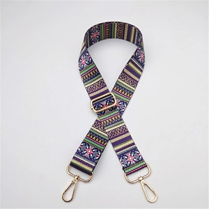 Close-up of adjustable woven fabric bag strap with colorful ethnic pattern and gold hooks