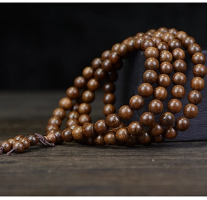 Macro shot of 108 sandalwood prayer beads showing natural wood grain and mystic knot