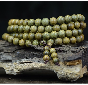 Détail de 108 perles de prière en bois de santal vert sur un socle en bois