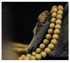 Macro detail of Thuja wood prayer beads with natural grain texture on dark wood branch