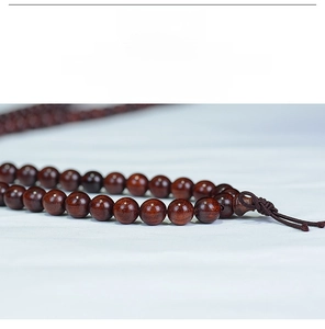 Macro shot of polished sandalwood prayer beads with deep red wood grain and glossy finish