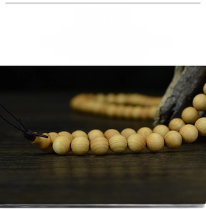 Macro shot of 108 Thuja beads with natural wood grain and polished oily texture