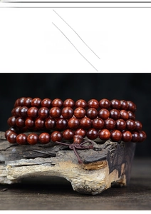 Detailed view of polished red sandalwood beads on a weathered wood background